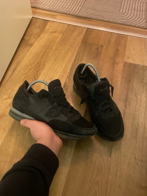 Svarta sneakers från Philippe Model - Snygga svarta sneakers från Philippe Model med en mix av mocka och mesh. Skorna har lågt skaft, svarta skosnören och diskret logga på plösen. Perfekta för en stilren och urban look. Obs det är glitter på färgen 