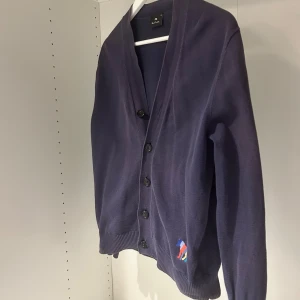 Mörkblå kofta från PS Paul Smith  - Stilren mörkblå kofta från Paul Smith. knappar framtill med en klassisk v-ringning. Storlek är XS men passar S också. Hör av dig vid minsta lilla fundering! 