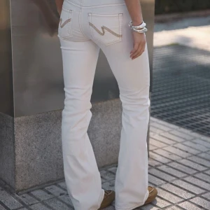 Vita lowwaist jeans - Snygga vita jeans med bootcut-modell och låg  midja. Design på bakfickorna och dubbla knappar. Säljer pågrund av att de är för små för mig!