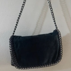 Mörkblå axelväska med kedja - Snygg mörkblå axelväska i mjuk mocka likande  med avtagbar kedjerem och detaljer längs kanterna med lite glittrig tyg. Påminner om den populära Stella McCartney väskan, stilren och enkel att matcha med allt.🤍
