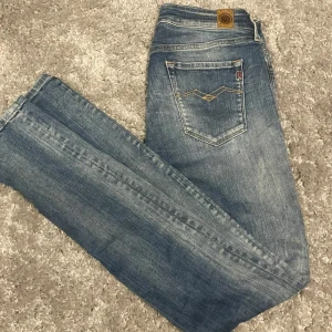  blåa Replay jeans med tvättningar och snygga detaljer - Blå jeans från Replay med tvättningar och snygga kontrastsömmar på bakfickan. Klassisk femficksmodell med Replay-logga på fickan och läderpatch bak i midjan. Jeansen har en slimfit passform och är tillverkade i mjukt denimtyg.