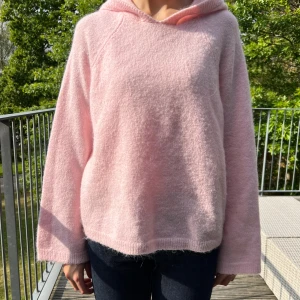 Ljusrosa stickad  hoodie från gina!! - Supermjuk och fluffig hoodie i ljusrosa med huva och avslappnad passform. Tröjan har långa ärmar och är tillverkad i ett stickat material som känns riktigt cozy. Perfekt för kyliga dagar när du vill vara både bekväm och söt.