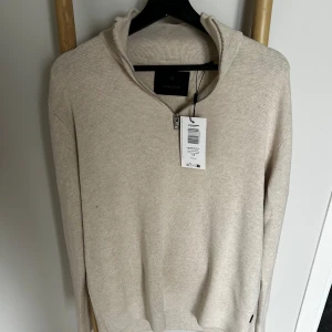 Beige stickad half zip *Nypris: 640kr* - Snygg beige stickad tröja från Jack & Jones Premium med half zip-dragkedja och hög krage. Tröjan har en clean look, lång ärm och ribbade muddar. Perfekt för lager-på-lager och passar till både jeans och chinos.
