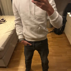 Vit hoodie med ficka och huva - Säljer en stilren vit hoodie med klassisk känguruficka och dragsko i huvan. Tröjan har lång ärm och ribbade muddar vid ärmslut och nederkant. Perfekt för dig som gillar en clean och enkel look. Passar xs oxå. 