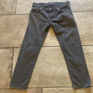 Svarta byxor från Jacob Cohen - Snygga svarta byxor från Jacob Cohen med klassisk femficksdesign och raka ben. Byxorna har silverfärgade detaljer och är tillverkade i ett mjukt bomullsmaterial som ger en skön känsla. Perfekta för dig som gillar stilrena och tidlösa plagg. Jeansen har inga defekter och kommer i slim fit. Är W36 och är 100cm på längden 