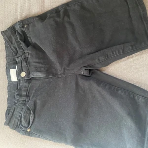 Svarta jeansshorts från D.M.D - Svarta jeansshorts från D.M.D med klassisk femficksdesign, knapp och dragkedja framtill. Shortsen har en rak passform och är tillverkade i ett slitstarkt jeanstyg som passar perfekt till sommaren. Snygga att matcha med en t-shirt eller hoodie.