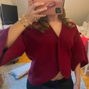 Vinröd kofta från Dagmar - Säljer en vinröd kofta från Dagmar med v-ringad hals och vida trekvartsärmar. Koftan är i modellen bea 