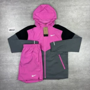 Nike vindjacka rosa och grå - Sportig vindjacka från Nike i en snygg kombo av rosa, grått och svart. Jackan har huva, hel dragkedja och två fickor med rosa detaljer. Perfekt för dig som gillar streetwear och vill sticka ut med färg.