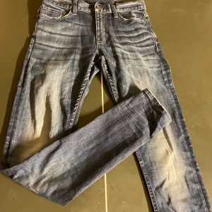 Mörkblå jeans från Crocker i slim fit - Crocker jeans i blå tvätt med snyggt slitna detaljer och raka ben. Jeansen har fem fickor, knappgylf och en ikonisk läderpatch bak i midjan. Perfekta för dig som gillar en tidlös och avslappnad look.