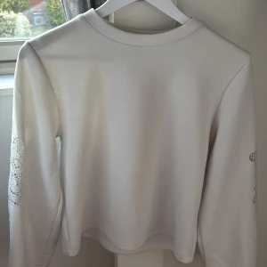 Vit långärmad tröja med spetsärm Kappahl - Vit långärmad tröja från Kappahl i storlek XS. Tröjan har snygga spetsdetaljer på ärmarna som ger en unik touch. Mjuk och skön bomullskänsla, perfekt till både jeans och kjol. Enkel rund halsringning och rak passform.