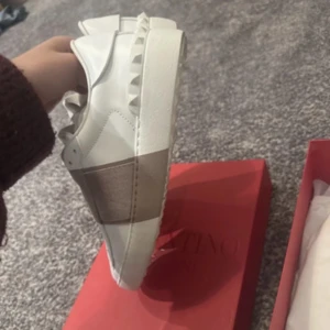 Valentino sneakers - Snygga sneakers från Valentino Garavani med bred beige/rosa rem över foten och nitar på hälen. Skorna är i skinn. Ny pris ca 6000 säljer för 3000 Max och kan ta emot bud. Knappt använda