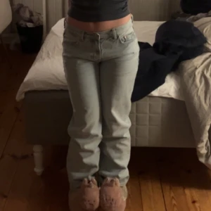 Ljusblå raka jeans - Säljer ett par ljusblå jeans med rak passform och klassisk femficksdesign. Jeansen har hög midja och är tillverkade i ett mjukt denimtyg som ger en avslappnad look. Perfekta för dig som gillar en enkel och stilren stil.