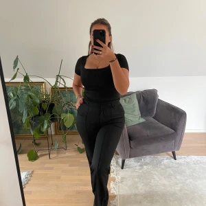 Svarta kostymbyxor med hög midja - Säljer ett par svarta kostymbyxor med hög midja och raka ben. Byxorna har bälteshällor, fickor fram och en klassisk, stilren look. Perfekta att styla med crop tops eller skjortor för en clean vibe.