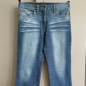 Blå randiga bootcut jeans Terranova - Snygga blå jeans från Terranova med tunna vita ränder och bootcut-modell. Jeansen har klassisk femficksdesign, normal midja och är tillverkade i denim med lätt tvättad effekt. Perfekta för dig som gillar en retroinspirerad look med lite extra edge. Midjemått 75/76 cm 