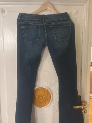Blå bootcut jeans med hål - Säljer ett par blå bootcut jeans med snygga hål på framsidan.Passformen low waist bootcut med lite utsvängda ben och de har en cool, avslappnad vibe.