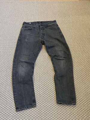 Jack & Jones jeans - Gråa jeans från Jack & Jones. Boxarna är i storlek 28/32 men jag skulle säga att midjan är mer som 29 och längden är mer som 30. Byxorna har ett litet hål (syns på bild 3).