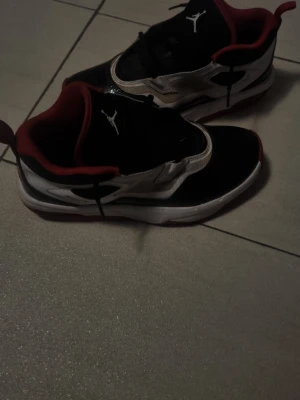 Nike Air Jordan Flight sneakers - Säljer ett par Nike Air Jordan Flight sneakers med svart, vit och röd färg. Skorna har snörning, rund tå och platt sula. 