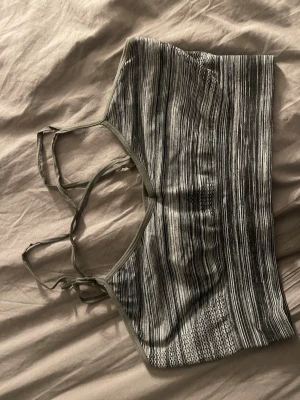 Randig grå linnetopp från InMotion - Säljer en randig grå linnetopp från InMotion med smala axelband och quickdry-funktion. Toppen har ett sportigt utseende och är perfekt för träning. Materialet är syntet och elastan, vilket gör den både bekväm och följsam.