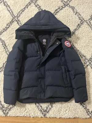 Canada goose McMillan  - McMillan i storlek M inga skador eller liknande defekter full med dunn använd bara en säsong  Jackan är mörkblå jag är 185 på bilden
