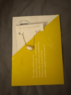 Kendra Scott - Bilderna visar ett halsband från Kendra Scott med ett vitt opal-liknande hänge och guldfärgad kedja, samt tillhörande förvaringspåse. Fick den i julklapp men använder tyvärr silver 💞☺️