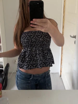 Blommig topp💗 - supersöt bandeau topp från gina tricot i svart med vita små blommor💓toppen har axelband som inte syns tydligt på bilderna💕har en volang nedtill 🩷kom ej till användning 💓