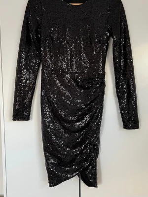 Svart glittrig klänning från NLY Trend - Säljer en svart glittrig klänning från NLY Trend i storlek 34. Klänningen har lång ärm, paljetter över hela ytan. Klänningen är perfekt för fester eller bara som en nyårsklänning. Använt endast en gång. 