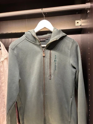 Mörkgrön Sail racing zip up hoodie - Mörkgrön sail racing Zip hoodie. Modell jr bowman zip hoodie. Nypris 1000kr säljer för den är för liten. Storlek 176 barnstorlek. Bra skick utan defekter. Är öppen att diskutera pris 