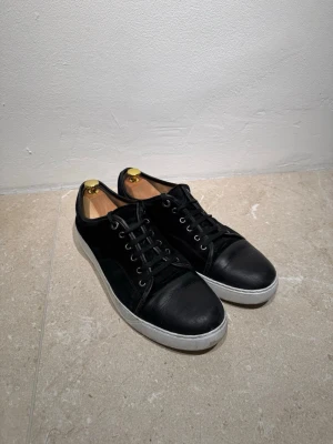 Lanvin  - Svarta sneakers från Lanvin i mocka och Capote i nappa. Skorna har rund tå, snörning med metallöglor och vit platt sula med Lanvin-logga undertill. Perfekt för dig som gillar stilrena och klassiska sneakers med exklusiv känsla.                  !!!!Priset går att diskuteras!!!!!!