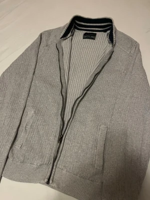 Stickad cardigan/ kofta - Fin stickad kofta / cardigan med dragkedja, passar till allt och är väldigt clean. Perfekt under en t shirt eller en skjorta vid finare tillfällen. Fint skick, storlek L men sitter mer som S. Skriv vid minsta intresse, pris kan alltid diskuteras vid smidig affär😀