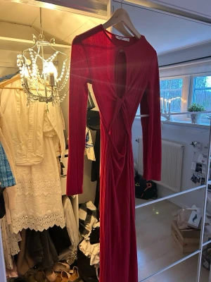 Röd långklänning - Säljer en röd långklänning med lång ärm och cut-out detaljer framtill.