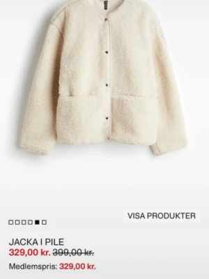 Beige teddyjacka med knappar - Mysig beige teddyjacka i pilematerial med rund hals och tryckknappar framtill. Jackan har två stora fickor och lång ärm, perfekt för lager-på-lager och chill dagar. Enkel och stilren design som är lätt att matcha.