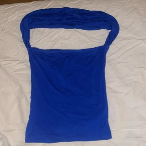 Blå bandeau tubtopp från NA-KD - Säljer en snygg blå bandeau tubtopp från NA-KD i storlek XS. Toppen har en axelbandslös design med bred överdel som kan stylas på olika sätt. Mjuk och stretchig känsla, perfekt för att skapa en cool och trendig look.