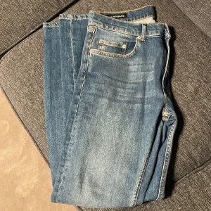 Blå jeans från J.Lindeberg, 32/32 - Snygga blå jeans från J.Lindeberg i klassisk femficksmodell med kontrastsömmar och metallknappar. Jeansen har en diskret logga på myntfickan och är tillverkade i slitstarkt denim. Passar dig som gillar stilrena och tidlösa jeans. Skick 10/10. Nypris 1200kr. Pris kan diskuteras