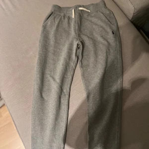 Grå mjukisbyxor Polo Ralph Lauren - Snygga grå mjukisbyxor från Polo Ralph Lauren med klassisk broderad logga på höften. Byxorna har snörning i midjan, sidofickor och är tillverkade i mjukt bomullsmaterial. Perfekta för chill eller träning, riktigt sköna och stilrena.