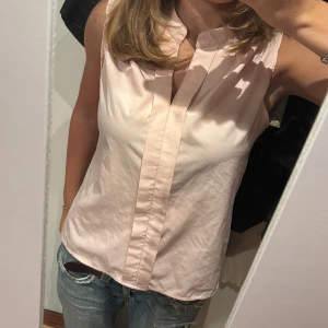 Ljusrosa ärmlös blus från KEBUNUO - Säljer en ljusrosa blus från KEBL med snygg krage och v-ringad hals. Blusen är ärmlös då den har blivit omsydd.