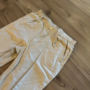 Beige linnebyxor med snörning - Snygga beige linnebyxor med elastisk midja och snörning för extra komfort. Byxorna har raka ben, sidofickor och en bakficka. Perfekta för chill dagar och har en avslappnad passform som ger en skön vibe.