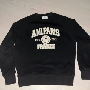 Svart sweatshirt från Ami Paris - Snygg svart AMI Paris tröja!!  passar till allt – jeans, mjukisar. Finns ett tryck på framsidan som det står “AMI PARIS FRANCE EST. 2011” i vit/beige text 🇫🇷 riktigt lugn o stilren vibe ✨ bra skick, bara använd ett fåtal gånger (5-10) gånger. Vid minsta fundering är det bara att fråga.😃