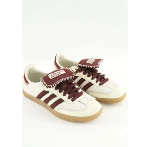 Adidas Wales Bonner Samba sneakers - Adidas Wales Bonner Samba sneakers i vitt och vinrött med klassiska tre ränder på sidan. Skorna har en unik design med kontrasterande broderad kant på plösen, snörning och detaljer i skinn och mocka. Yttersulan är i gummi och modellen har en platt sula och rund tå.