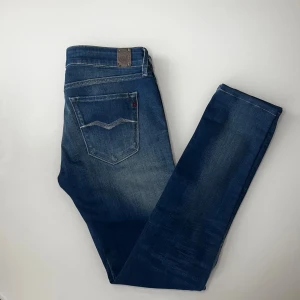 Replay Luz Jeans - Snygga blå jeans från Replay med klassisk femficksdesign och diskret slitning. Jeansen har raka ben och tydliga kontrastsömmar samt Replay-logga på bakfickan och läderpatch i midjan. Perfekta för en avslappnad och stilren look.