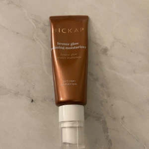 Hickap Bronze Glow Priming Moisturizer - Bronze Glow Priming Moisturizer från Hickap i en snygg bronsfärgad tub med pump. Ger huden en fräsch glow och fungerar både som primer och återfuktande kräm. 100% vegansk och passar alla hudtyper. Perfekt för dig som vill ha en naturlig lyster.