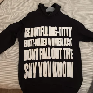 Svart hoodie Lost Boys XS med tryck - Svart hoodie från Lost Boys i storlek XS med stor vit text på framsidan och broderad logga på huvan. Klassisk passform med långa ärmar och mjukt material, perfekt för dig som gillar streetwear och statement-plagg.