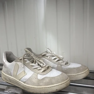 Beige och vita Veja sneakers - Snygga sneakers från Veja i beige och vitt med klassisk V-logga på sidan. Skorna har rund tå, platt sula och snörning. Säljs då jag ej använder längre, syndligt använda men inga större defekter.