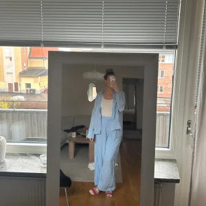 Ljusblått set från Gina Tricot - Säljer ett ljusblått set från Gina Tricot i mjukt och luftigt bomullsmaterial. Skjortan har klassisk krage, långa ärmar med manschett och knappar framtill. Byxorna har vida ben. Jag är 175cm lång och byxorna är bra i längden.