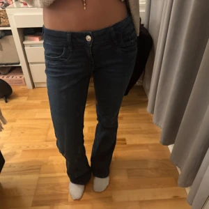 Mörkblå bootcut jeans - Säljer ett par mörkblå lågmidjade jeans från ginatricot. Jeansen sitter snyggt över höfterna och låren. Det finns spännen i byxorna så man kan justera de. Säljer eftersom de aldrig använts! De är i storlek 164 men passar mig som ofta har s och är 167 cm!