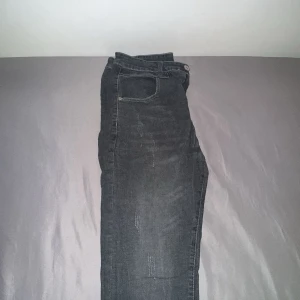 Svarta jeans med raka ben - Säljer ett par svarta jeans med raka ben och klassisk femficksdesign. Jeansen har stora bakfickor och en lätt tvättad look för en avslappnad vibe. Passar perfekt till sneakers eller boots och är tillverkade i mjukt denimtyg.