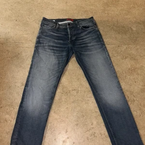 Jack & Jones Slim Glenn jeans blå 32/30 - Snygga blå jeans från Jack & Jones, modell Slim Glenn. Jeansen har en slim passform, klassisk femficksdesign och snygga slitningar framtill och baktill. Tillverkade i stretchig denim för extra komfort. Perfekta för en avslappnad och trendig look.