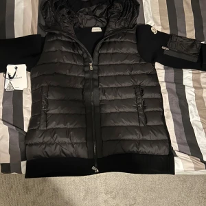 Moncler cardigan  - Moncler cardigan med Moncler-logga på ärmen och extra ficka med dragkedja på sidan. Perfekt för lager-på-lager under kyliga dagar. Jackan kan användas året runt och i storlek M tveka inte på att höra av er