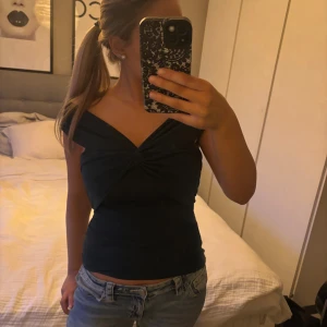 mörk grön omlott tubtopp med twist - Snygg mörk grön tubtopp med omlott-twist framtill som ger en cool och unik look. Toppen är axelbandslös och sitter tight mot kroppen, perfekt till jeans eller kjol. Materialet känns mjukt och stretchigt, vilket gör den bekväm att bära. Passar dig som gillar stilrena och trendiga plagg.