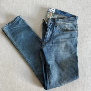  Acne Studios Jeans - Snygga blå jeans från Acne Studios med raka ben och smal passform. Lagning i grenen gjord proffsigt hos skräddare, sista bilden visar hur det ser ut från utsidan. Synns inte alls vid användning. Storlek 31/32. Hojta gärna vid eventuella frågor