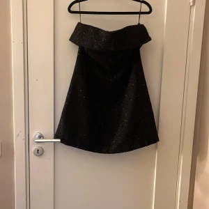 Svart glittrig klänning från H&M - Supersnygg svart glittrig klänning från H&M i A-linjeformad modell. Kjolen har en bred linning och är tillverkad i ett glittrigt tyg som ger en lyxig känsla. Perfekt för dig som vill sticka ut med en elegant och trendig look. Perfekt till nyår aldrig använt men jag som har storlek 36 eller 38 kan ha den bara att den kan vara lite stor vid brösten. Fråga om fler bilder!